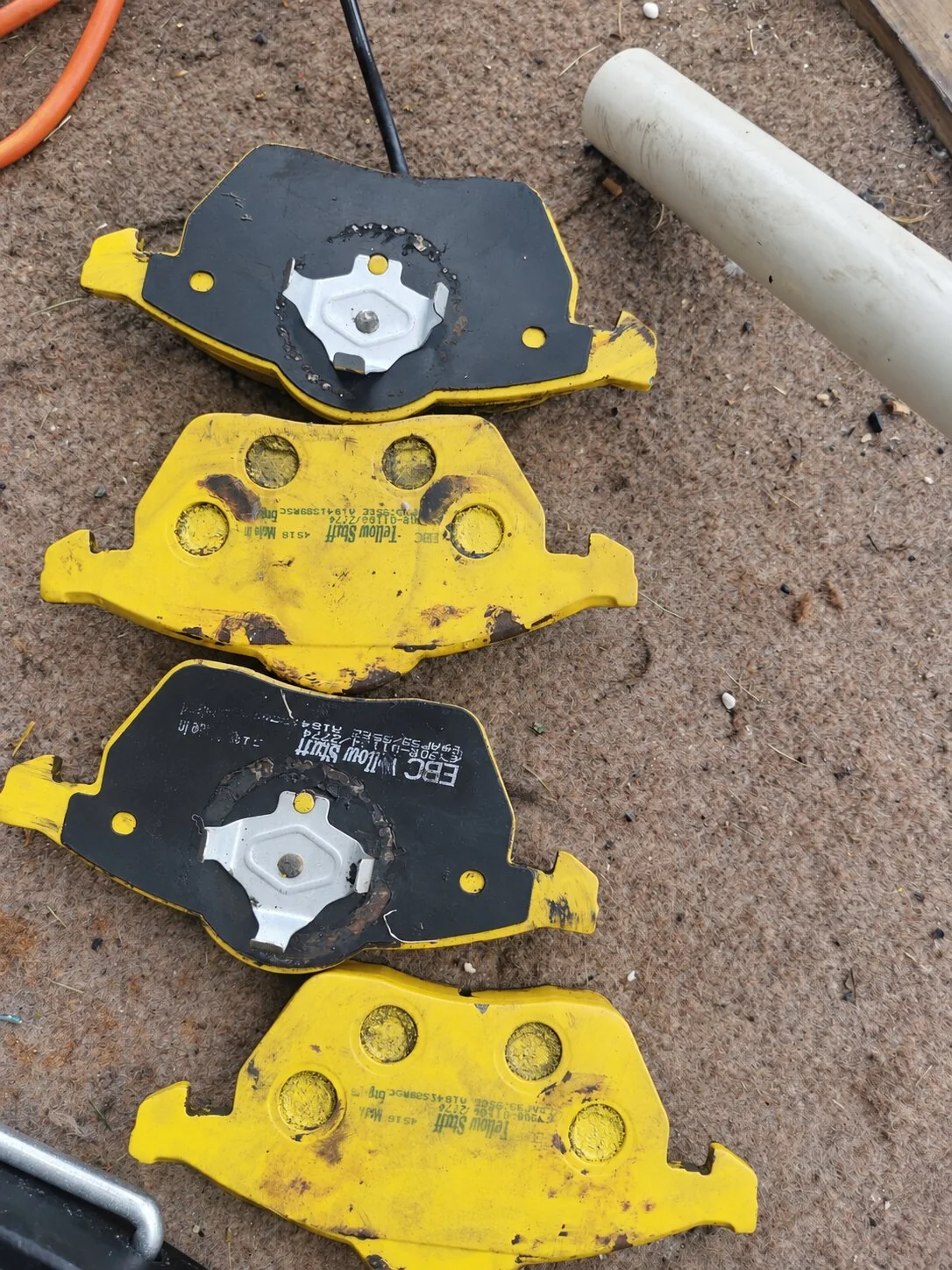 Used yellow-backed EBC brake pads laid out for inspection