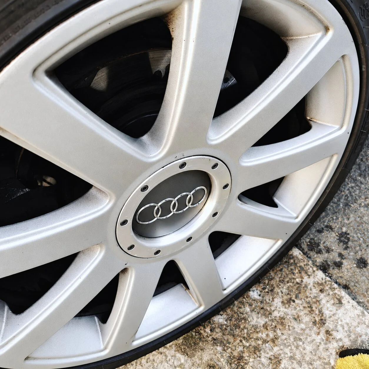 Silver Audi alloy wheel with visible dirt around the spokes